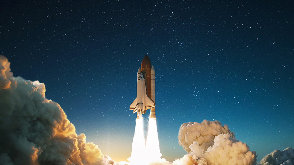 A space shuttle blasts off towards space, leaving clouds of smoke behind. A starry sky is visible in the background. Un transbordador espacial despega hacia el espacio, dejando detrás nubes de humo. Al fondo se ve un cielo estrellado