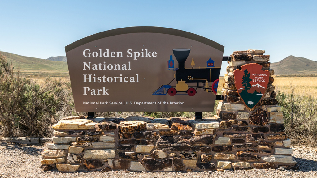 A sign by the National Park Service says Golden Spike National Historical Park with an image of a train.