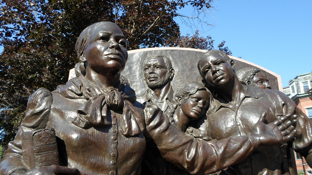 A bronze sculpture shows Harriet Tubman bravely leading a group of formerly enslaved people forward